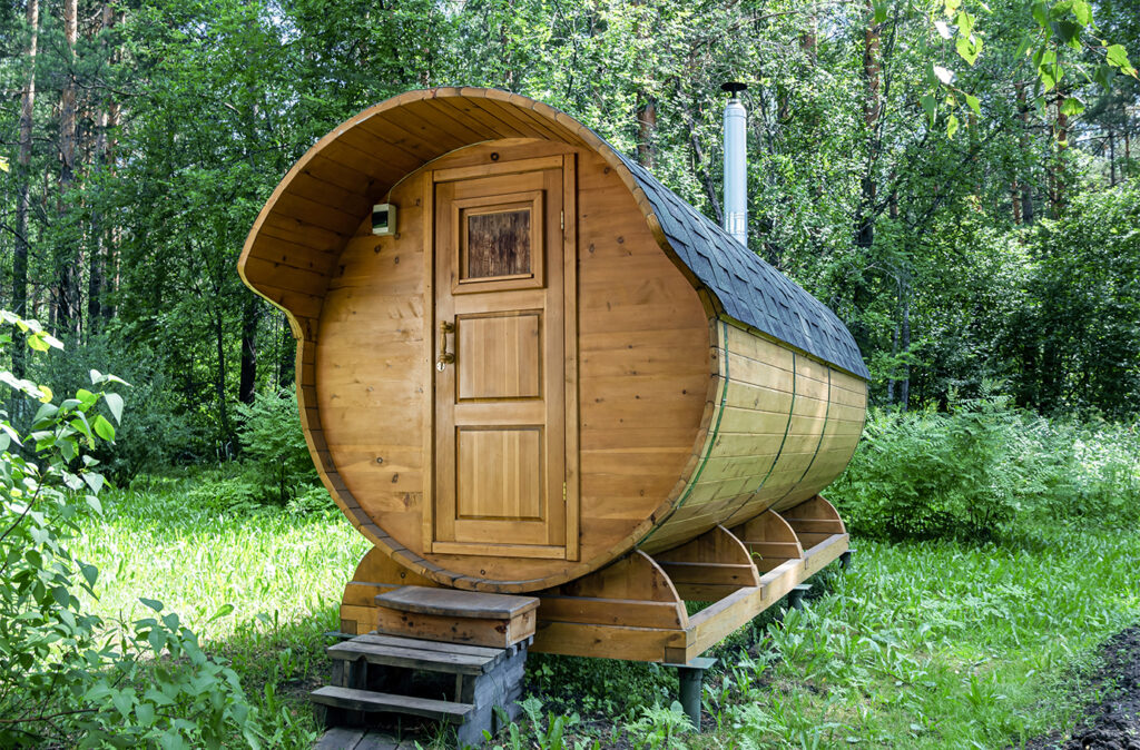 Round wooden barrel bath stands in the forest on a sunny summer day