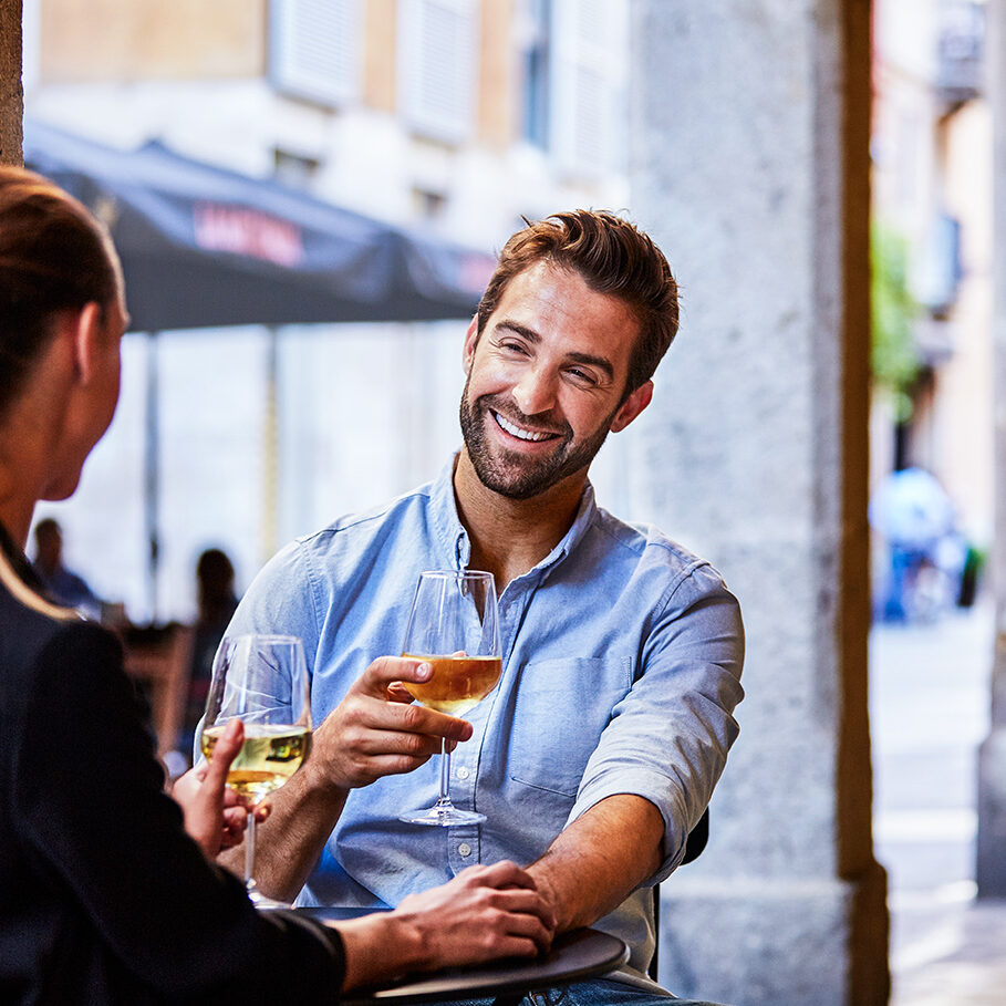 Shot of a young couple sitting at a sidewalk table drinking wine and talking together