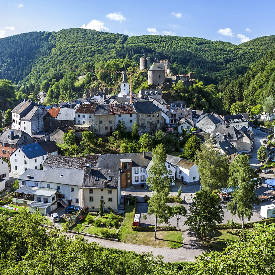 Esch-sur-Sure is a small town near Luxembourg city that sits in a little circle of land within a sharp curve of the river Sure. It is very picturesque and has the ruins of an old castle on top of the hill. The town is surrounded by lush, green trees.