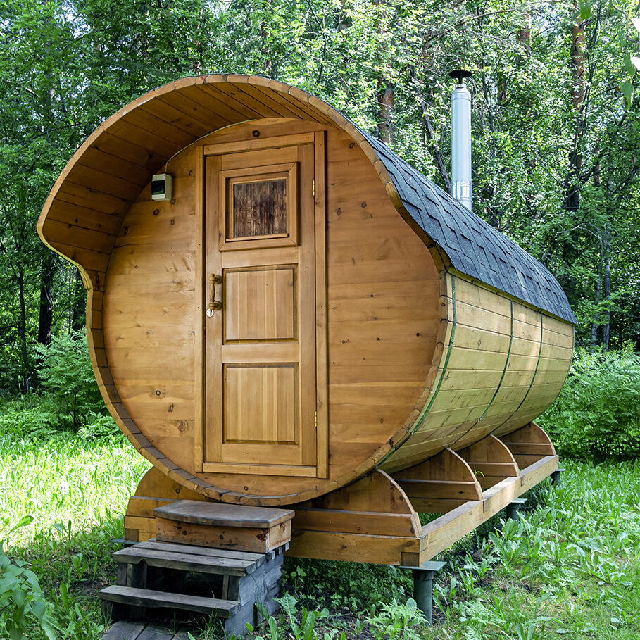 Round wooden barrel bath stands in the forest on a sunny summer day