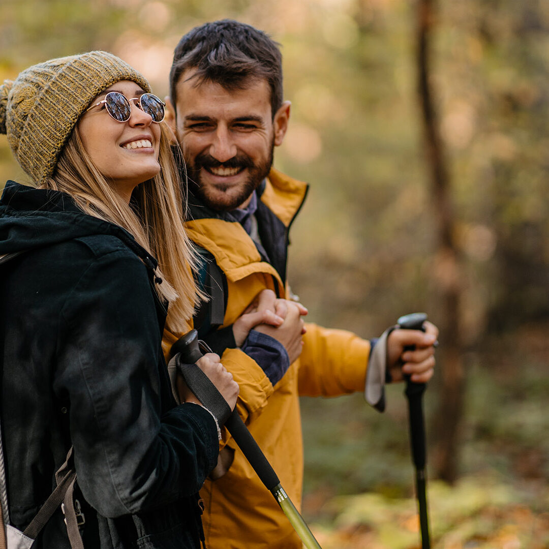 Young couple hiking. Hugging and smiling while walking and having a good time together