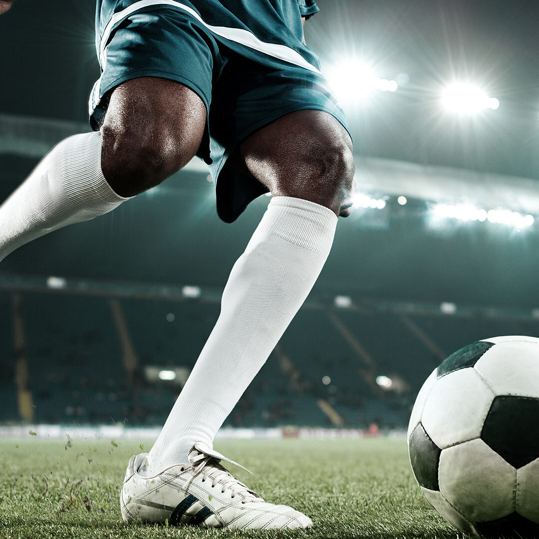 Soccer player kicking the ball at the stadium. The stadium is made in 3D.