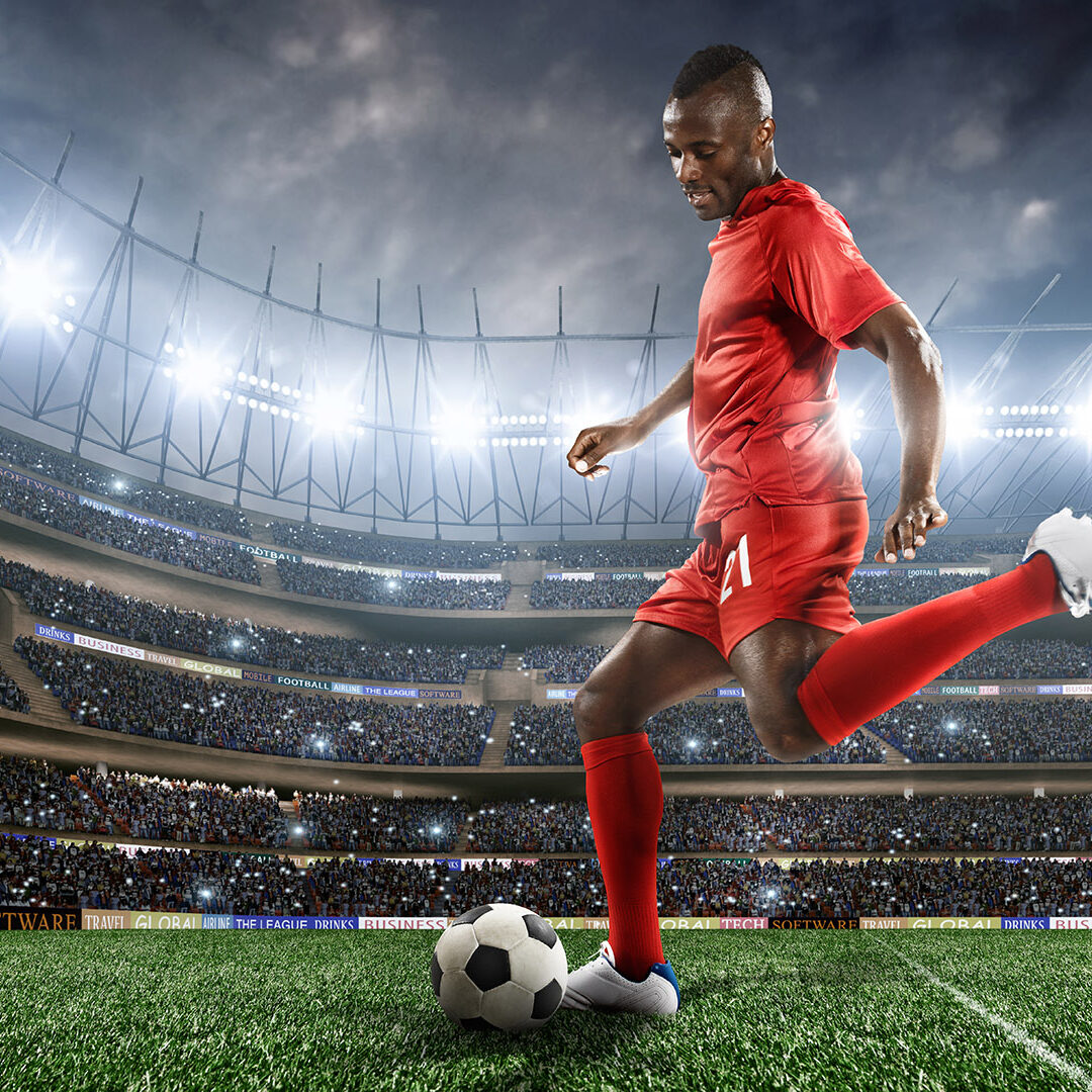 Close up of professional footballer playing in floodlit stadium