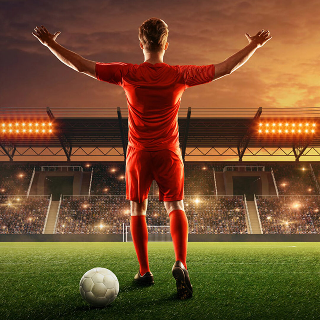 Professional soccer player with a ball on a floodlit stadium. Night soccer stadium with fans cheering and dramatic sky. Sports event. Celebrating the victory