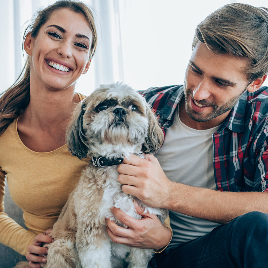 Shot of an affectionate young couple relaxing with their pet dog on the sofa at home.