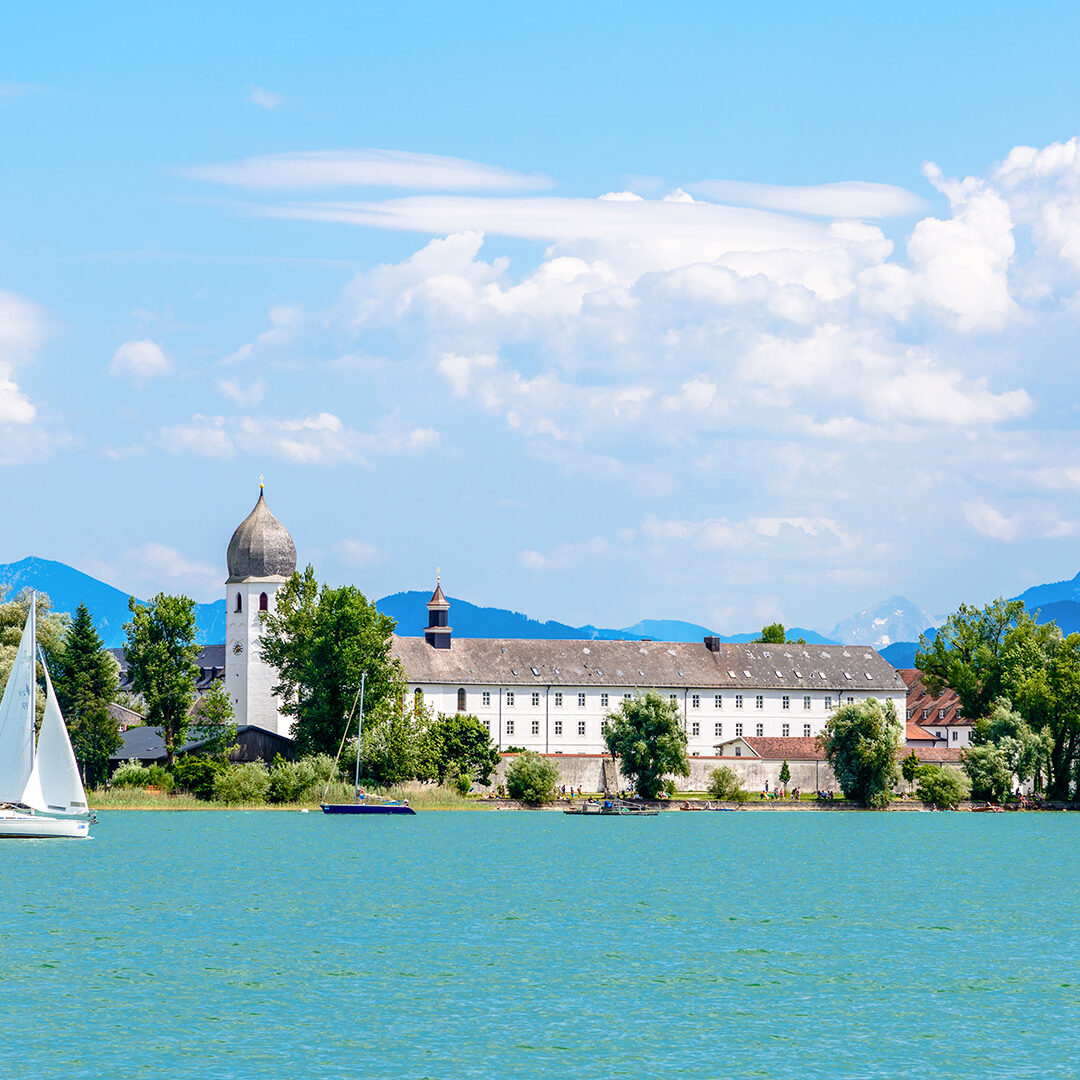 Lake Chiemsee with a boat, sailboat, church, blue sky. clouds. Bavaria, Germany